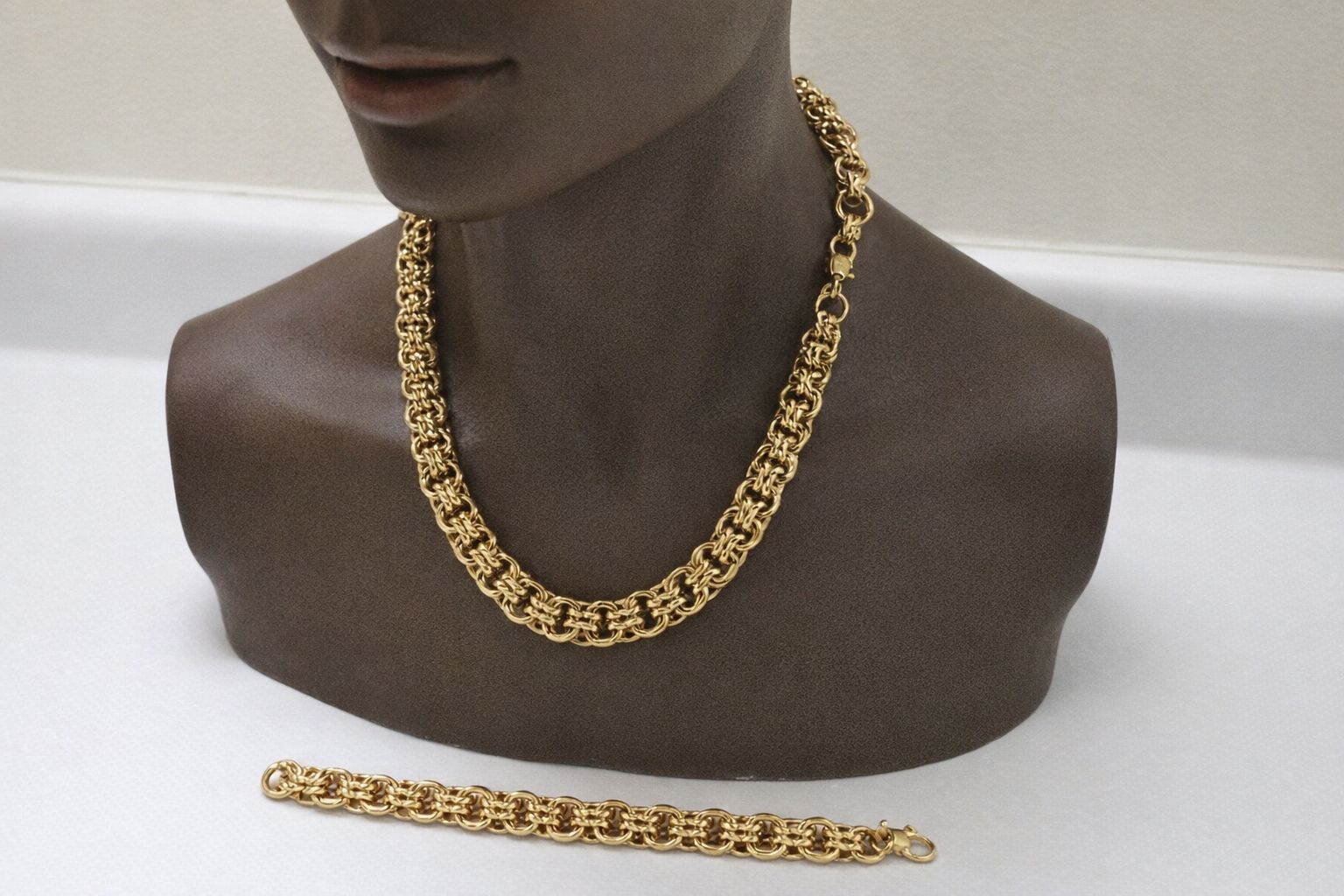 Ett kraftigt bismarckhalsband i guld på en byst med matchande armband.