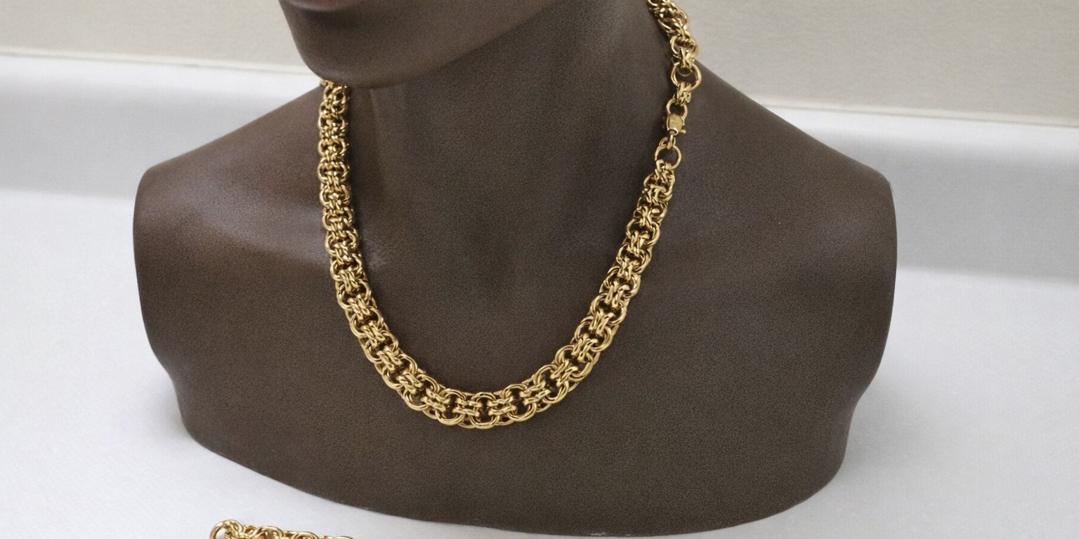 Ett kraftigt bismarckhalsband i guld på en byst med matchande armband. Ett kraftigt bismarckhalsband i guld på en byst med matchande armband.