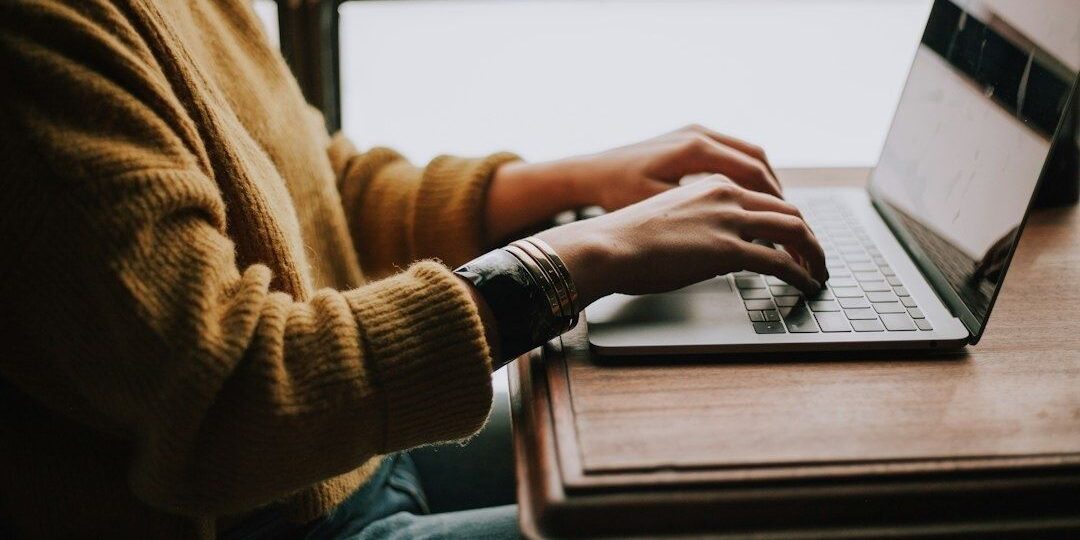 Person skriver på en bärbar dator vid ett fönster